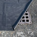 A grate with a black mat over it, sealing the drain