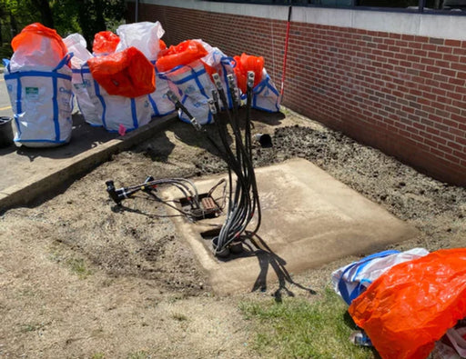Several opened Spill Bully Drum Packs around a concrete slab with several large wires coming out of the ground 