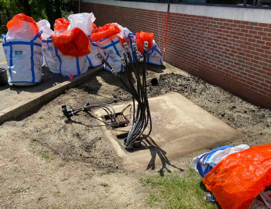 Several opened Spill Bully Drum Packs around a concrete slab with several large wires coming out of the ground 