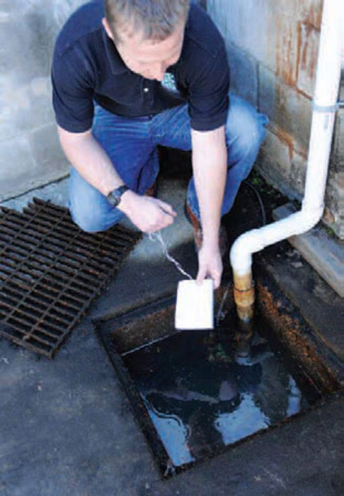 A man puts an Ultra-Archaea boom in a drain