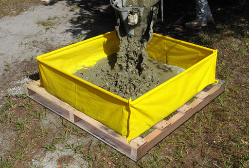 A yellow washout berm on top of a pallet with concrete mix being poured into it